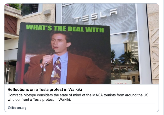 A protest sign in front of a Tesla show room in Waikiki reads "What's the Deal with all the burning Teslas?" and shows a 1980s Jerry Seinfeld asking the question.