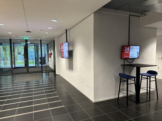An empty office hallway with two net presenter screens. Each net presenter shows a slide to announce today's strike, with the program.