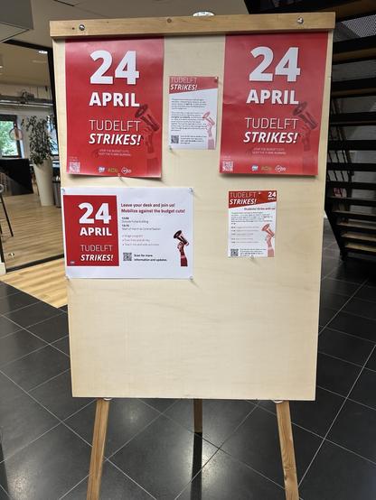 A poster board in an office building. The poster board is covered in flyers and posters announcing today's strike.