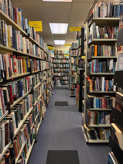 A long shot of an aisle of bookshelves, lots and lots of books.
