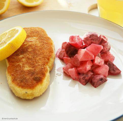 Weißer Teller. Darauf ein panierter Fisch aus Kartoffeln. Daneben Rote-Bete-Gurken-Apfel-Salat