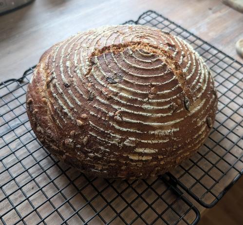 Ein Brot mit kleinem Sprung aber deutlichen Gärkörbchenrillen, ebenfalls auf einem schwarzen Auskühlgitter