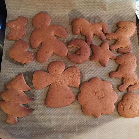 "Several colorful gingerbread cookies on parchment paper, likely for a festive occasion such as Christmas."