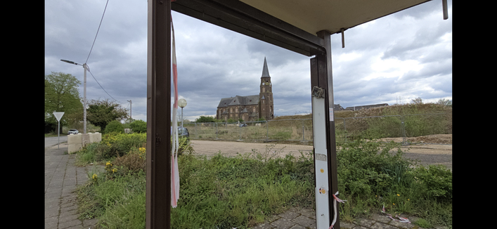 Blick durch die demolierte Manheimer Bushalte auf die Kirche