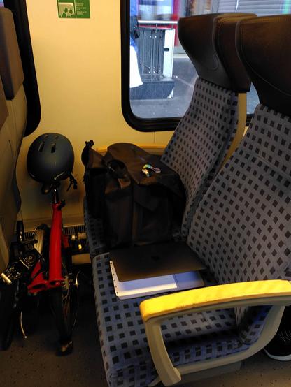 Fotobeweis
Ein rotes Faltrad passt gefaltet in die Sitzreihe des RE. Es bleibt Platz für Fahrradtasche und Radler*in mit Laptop.