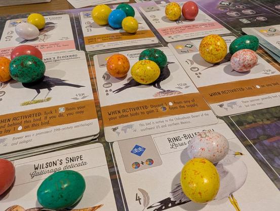 A photo of a Wingspan game mid play. The normal egg pieces are replaced with speckled egg m&ms