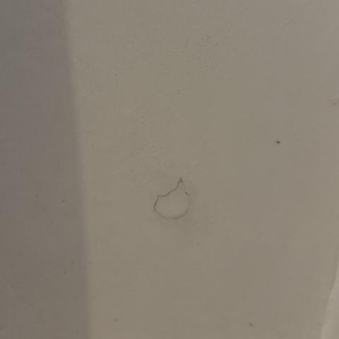 Mit Acryl geschlossenes Bohrloch in einer weißen Wand.