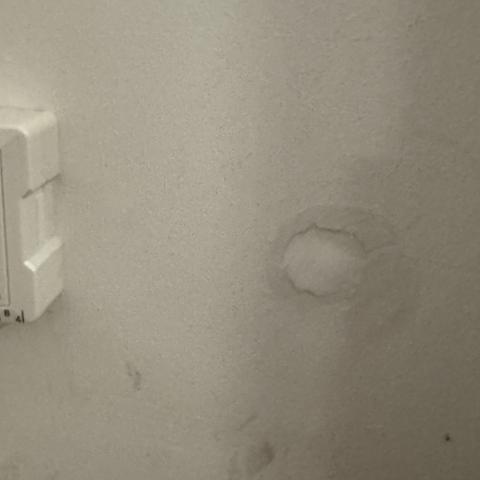 Mit Acryl geschlossenes Bohrloch in einer weißen Wand.