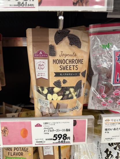 A shelf in a Japanese supermarket

A bag marked Joynuts Monochrome Sweets" by TopValu under the "Nuts & Joy!" marque 

The bag has graphics of oreos and chocolate bars 

Inside you can see white chocolate, chocolate, and crushed chocolate cookies