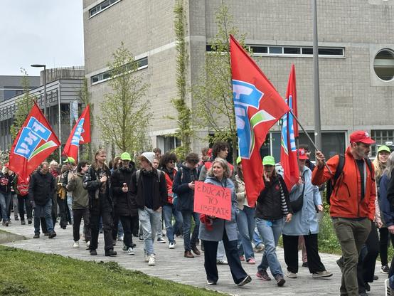 A crowd of marching protestors. A sign reads “educate to liberate”