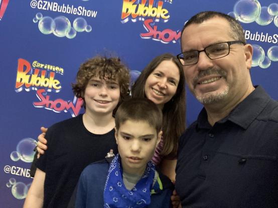 family selfie in front of step-and-repeat at New World Stages' Gazillion Bubble Show