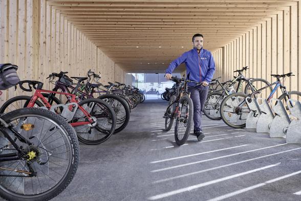Foto zeigt einen Mann mit Fahrrad in einer großen überdachten Fahrrad-Garage Bild: STUDIO22 MARCEL HAGEN