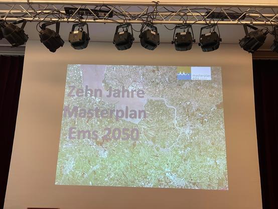 Titelbild eines Vortrages "10 Jahre Masterplan Ems 2050" auf einer Leinwand.