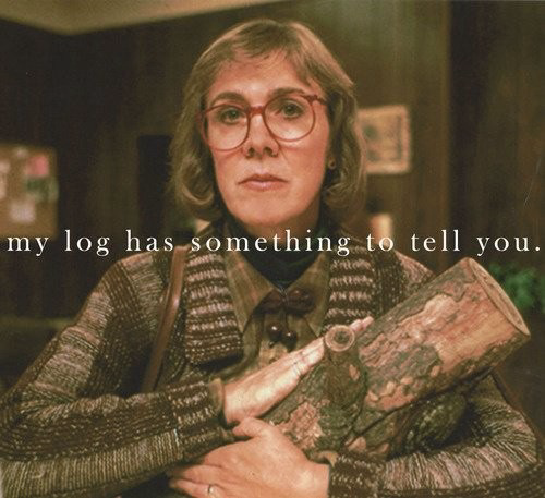 A screen capture from the TV show Twin Peaks. A woman in a sweater is holding what looks to be firewood, text on the screen reads “my log has something to tell you”