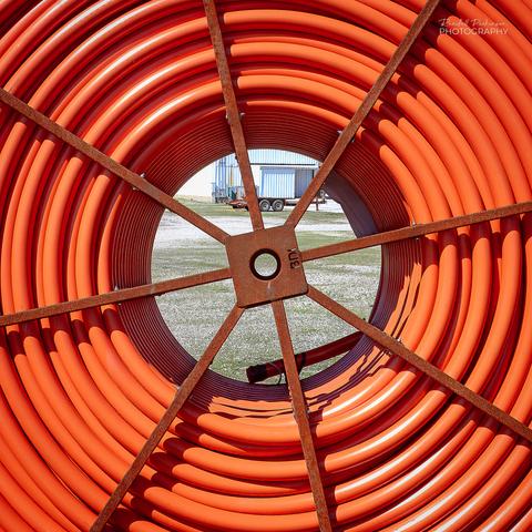 Closeup of a spool of orange wire conduit.