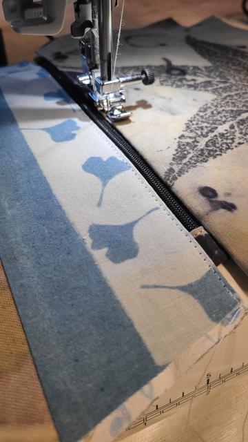 Alt tissu bleu clair avec réserve à la pâte de riz réalisée avec  un pochoir de petites feuilles de ginko biloba, plus en arrière plan empreinte de liquidambar en noir sur coton le tout en teinture végétale.
Trousse en train d'être cousue