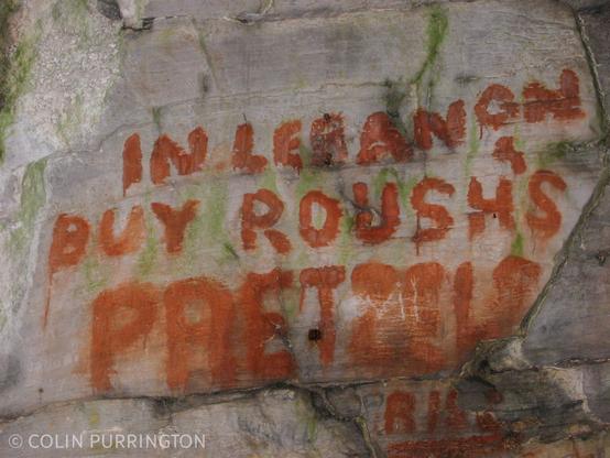 Painted block letters on a cave wall that say, "In Lebanon buy Roush's pretzels."