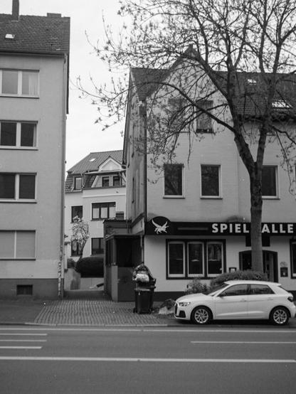 Black and white out-of-focus photo of a street with residential buildings and a gambling hall.