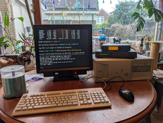 A picture of a desktop style compaq machine sitting on a circular wooden table looking out over a garden.