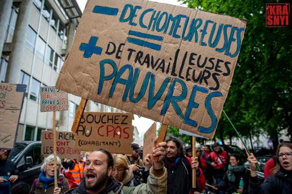Au dessus de la foule s'élève une pancarte "- DE CHOMEUR.EUSES = + DE TRAVAILLEURS.EUSE PAUVRES"