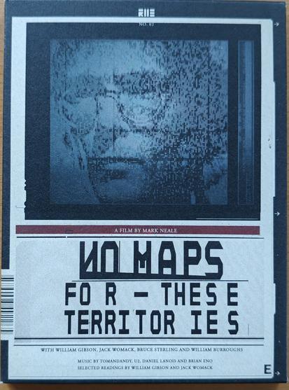 The front of the dvd box for the documentary "No maps for these territories". The top 2 3rds shows a black rectangle containing a lo-res/pixelized/glitchy portrait of William Gibson in dark grey tones. Below that a small text says "a film by Mark Neale". The main title takes up the bottom 3rd in a stylized angular font with strange kerning. Below that, in small print, is the text "With William Gibson, Jack Womack, Bruce Sterling and William Burroughs. Music by Tomandandy, U2, Daniel Lanois and Brian Eno. Selected readings by William Gibson and Jack Womack"