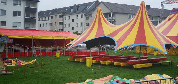 red and yellow striped circus tents in the rain, with no one around