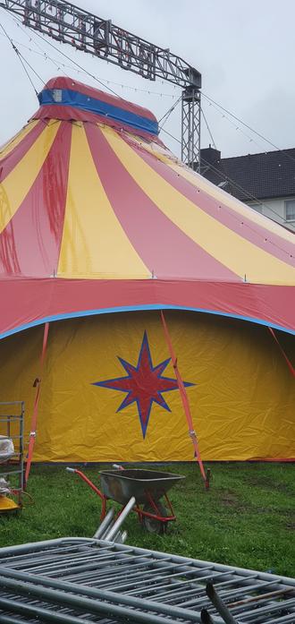 detail of a circus tent with wheel barrow and some temp fencing parts lying in front