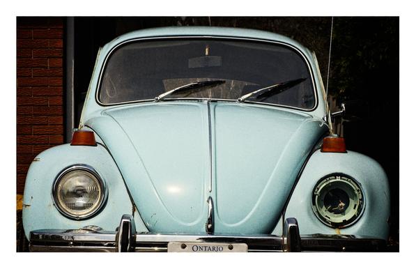 Old VW Beetle missing one headlight.