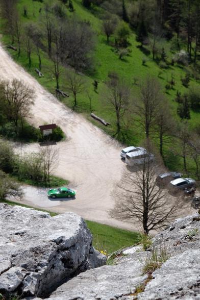 Blick von einem Felsen im Vordergrund hinab auf einen Wanderparkplatz mit einem grünen Porsche.

Looking from a rock down on a hiking parking lot with a green Porsche on it.
