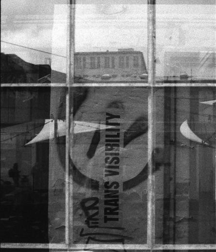 Eine Doppelbelichtung aus meiner unscharfen Spiegelung in einer Scheibe und dem Schriftzug "Trans Visibility"