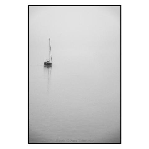 (English follows) Photographie noir et blanc, format portrait, ratio 2x3. L'image est prise un jour de brouillard et de faible clarté. Elle montre la Loire, qui occupe toute l'image dans des tons blancs et clairs. Sur la gauche de l'image, se découpe un petit voilier au mouillage, voile rangée. Son reflet se dessine sur l'eau. Sur les tons clairs de l'image, ce sont les seuls éléments, sombres, à se découper. 
Cette image est l'exact miroir de la première d'un triptyque présentant le même sujet (un bateau sur la Loire), elle clôt cet ensemble d'images, offrant un ensemble fait de tons clairs, de formes sur l'eau du fleuve. Sur le portfolio Pixelfed, les trois images sont alignées, dessinant un ensemble symétrique. 

Black and white photograph, portrait format, 2x3 ratio. The image was taken on a foggy, low-light day. It shows the Loire, which occupies the entire image in light, white tones. On the left-hand side of the image, a small sailboat stands at anchor, its sails furled. Its reflection can be seen on the water. In the light tones of the image, these are the only dark elements that stand out.
This image is the exact mirror image of the first of a triptych presenting the same subject (a boat on the Loire), and brings this set of images to a close, offering an ensemble of light tones and shapes on the water of the river. On the Pixelfed portfolio, the three images are aligned, creating a symmetrical whole.
