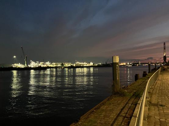 View on some part of the Hamburg harbor at dusk with a lot of lights on the other side of the water
