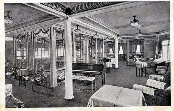 Interior d'un vaixell antic, d'un creuer de luxe, amb columnes i un piano al mig, fotografia en blanc i negre
