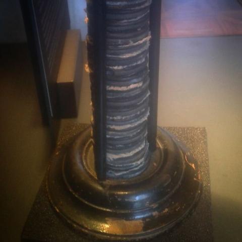 A stack of dark disks separated by white fabric, the stack is kept in place by three round rods and sits on a short circular plinth.