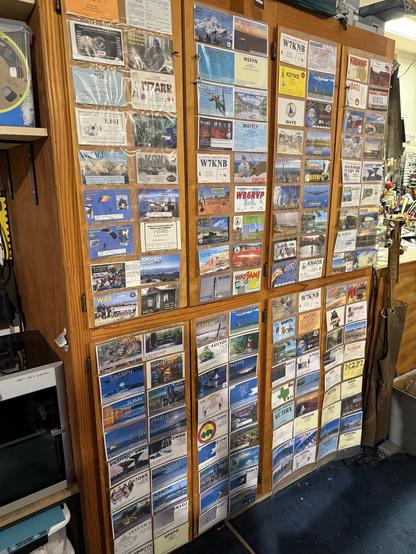 Eight sleeves of colorful QSL cards in clear plastic sleeves adorn garage cabinet doors.