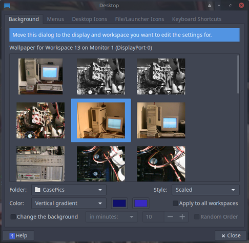 The image shows a desktop settings dialog box for selecting a wallpaper. The title at the top reads "Desktop" and includes tabs for "Background," "Menus," "Desktop Icons," "File/Launcher Icons," and "Keyboard Shortcuts." The main section of the dialog box is titled "Wallpaper for Workspace 13 on Monitor 1 (DisplayPort-0)" and features a grid of nine wallpaper images. The selected wallpaper is an image of an old computer setup with a monitor and keyboard. Below the grid, there are options for the folder ("CasePics"), style ("Scaled"), and color ("Vertical gradient"). Additional settings include a checkbox to "Change the background" every 10 minutes, a "Random Order" option, and a "Help" button. The dialog box also has a "Close" button in the top right corner.