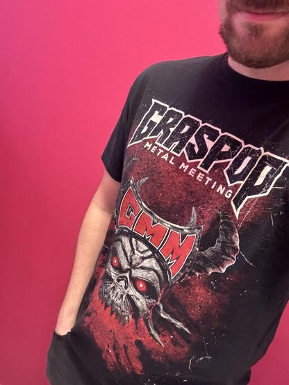 Ein Selfie, auf dem mein Oberkörper zu sehen ist, der in ein feines, schwarzes T-Shirt gewandet ist. Darauf ist in großen Buchstaben „Graspop Metal Meeting“ gedruckt. Darunter ist ein gemein dreinschauender Totenschädel mit Hörnern zu sehen.