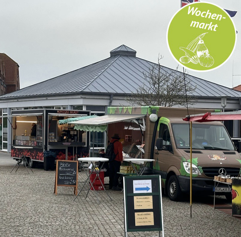 Zwei Imbisswagen auf dem Norddeicher Wochenmarkt vor dem Lesesaal hinterm Deich bieten ihre Waren an