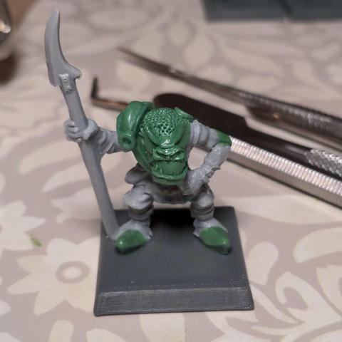 An in progress shot of a plastic model orc with various areas re-sculpted in epoxy putty