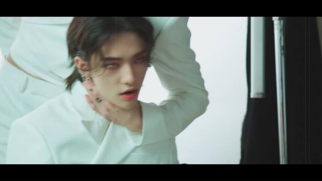 Scene from Red Lights MV making-of, where Hyunjin's sitting, Bang Chan's standing behind him, and has a hand around the front of his throat