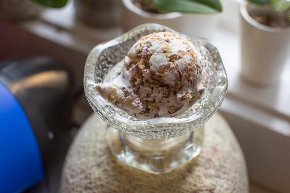 Scoop of nut-studded ice cream in a scalloped glass bowl.