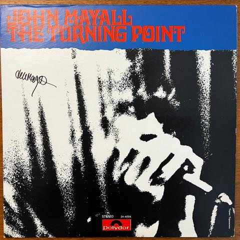 The Turning Point front cover – Underneath the title (in red type on blue background) is a stylized black and white mezzotint photograph that shows, in very abstract high contrast, a man holding a microphone cupped in his hands before his face. He appears to be surrounded by the folds of a curtain. This is probably from a photograph of John Mayall playing harmonica into a microphone, but the harmonica is not visible.

The album cover is signed in marker by John Mayall, in a squiggly signature.