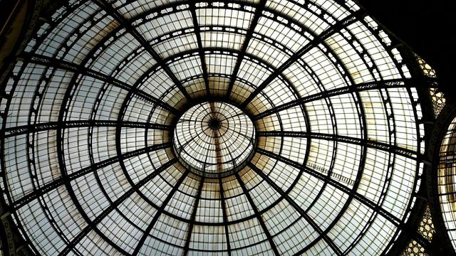 A detailed upward view of an ornate glass and metal domed ceiling with a circular pattern radiating outwards.