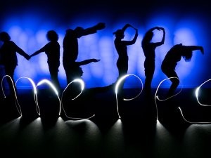 Das mittels Lightpainting gestaltete Logo des Zertifikatskurses in blau und schwarz. Von einem blau beleuchteten Hintergrund heben sich schemenhaft die Schatten von Menschkörpern ab. Zusammen bilden sie den Schriftzug "mepps". Dieser wurde noch einmal mit weißem Licht auf den schwarzen Boden geschrieben.