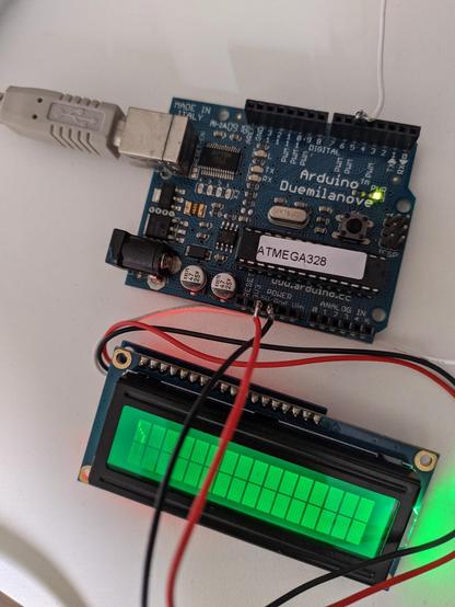 Blue Arduino Deumilanove microcontroller connected with a USB A cable. Red white and black wires are hooked up to an green tinted Lcd screen, where a squiggly line is shown. This line represents a Cilium, a haircell.