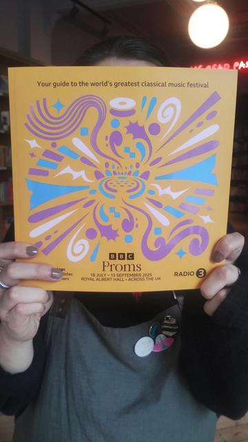 Bookseller Sarah holding up a copy of the 2025 BBC Proms programme in the Edinburgh Bookshop