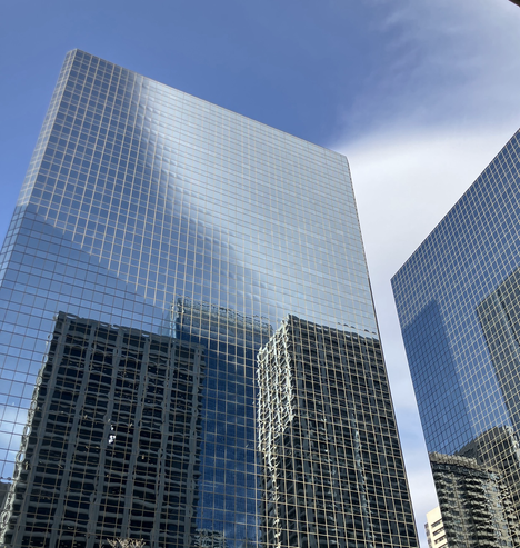 Photo of two glass skyscrapers with reflections of other buildings and sky