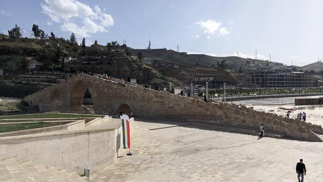 A Flag of Kurdistan in front of the Dalal bridge in sunshine.