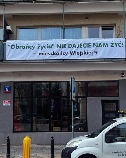 bezpośrednio nad witryną Abotak baner o treści:
"obrońcy życia" NIE DAJECIE NAM ŻYĆ
- mieszkańcy Wiejskiej 9