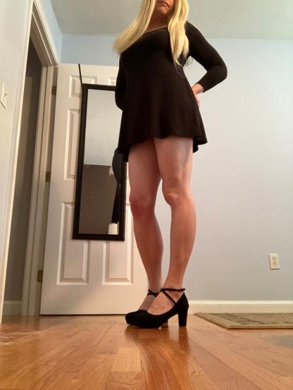 blonde woman with thigh length black dress and black strap high heels.